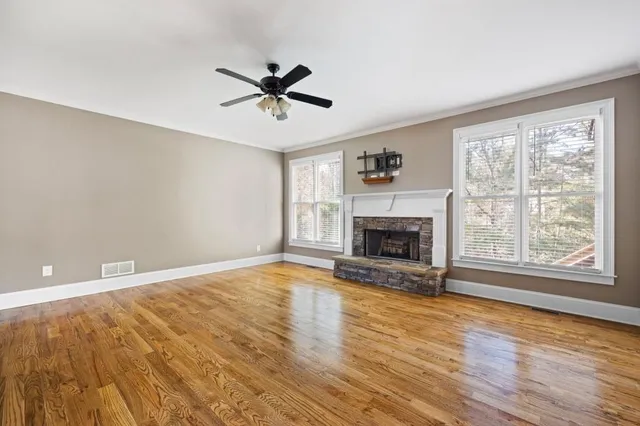 a view of an empty room with a window and wooden floor
