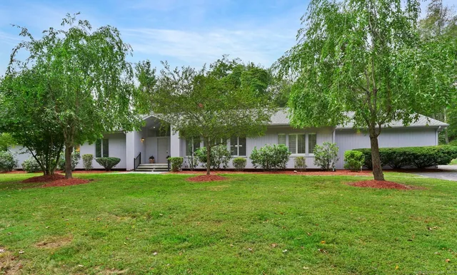 a front view of a house with a garden and trees