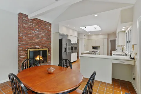 a kitchen with stainless steel appliances granite countertop a sink a stove a refrigerator a stove a dining table and chairs