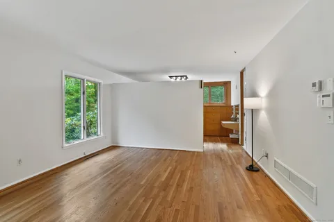 a view of a room with wooden floor a ceiling fan and a window