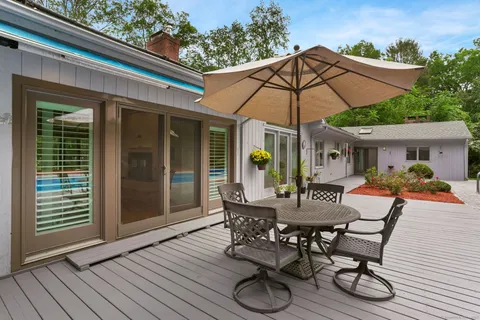 a view of a patio with table and chairs under an umbrella with wooden floor