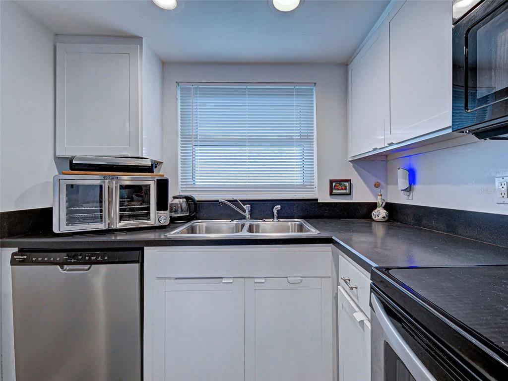 633 Alhambra Road, Unit 1006 Venice, FL 34285 - Photo 19 of 55 a kitchen with stainless steel appliances granite countertop a sink stove and microwave