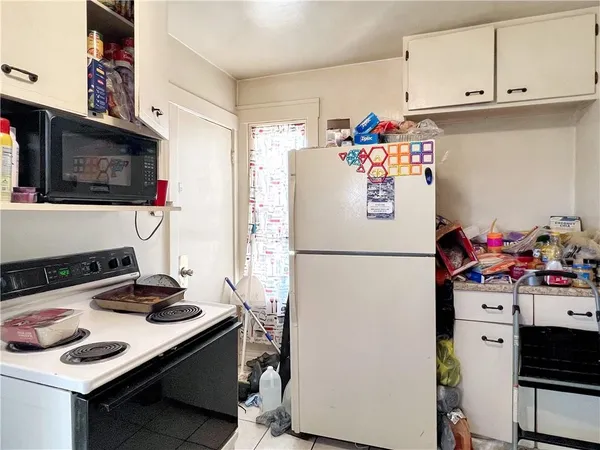 a white refrigerator freezer sitting in a kitchen with white cabinets