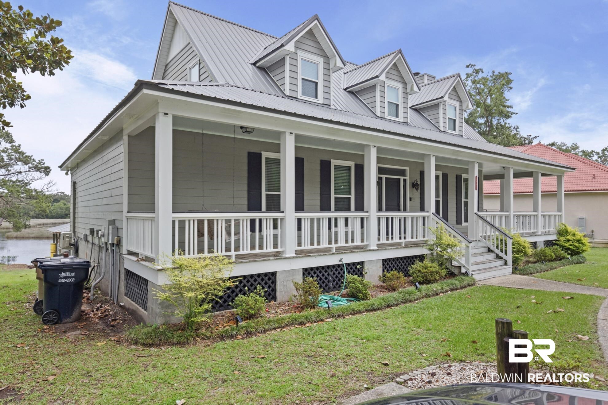 12171 Marguerite Drive Coden, AL 36523 - Photo 43 of 44 Coastal-inspired home featuring a metal roof, dormer windows, and a full-width covered porch with white railings