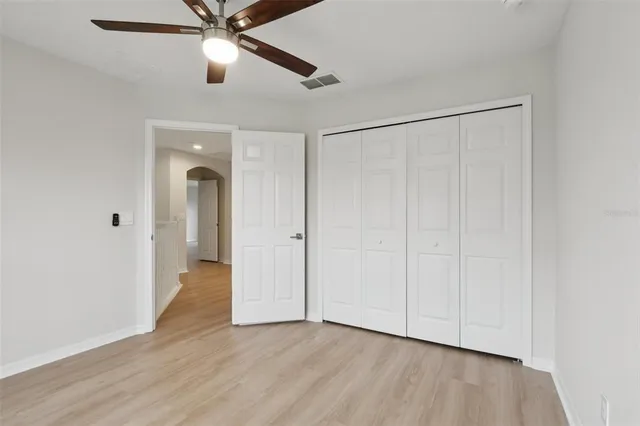 an empty room with wooden floor fan and windows