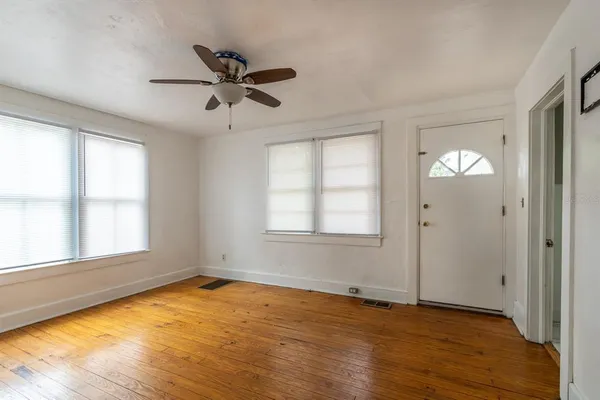 a view of empty room with wooden floor and fan