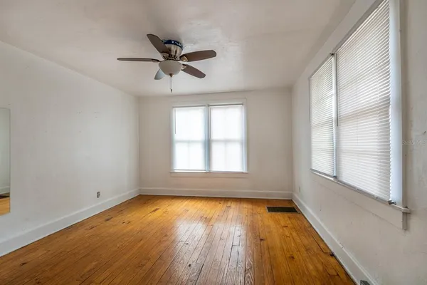 a view of empty room with wooden floor and fan
