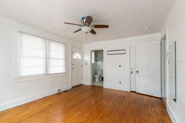 a view of empty room with wooden floor and fan