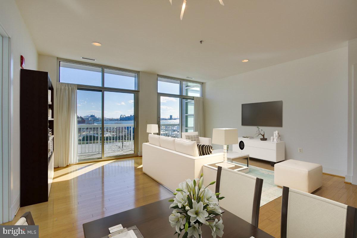 2772 Lighthouse Point East, Unit 308 Baltimore, MD 21224 - Photo 4 of 6 a living room with furniture a flat screen tv and a floor to ceiling window