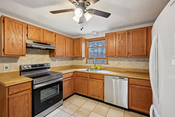 a kitchen with cabinets appliances a sink and a window