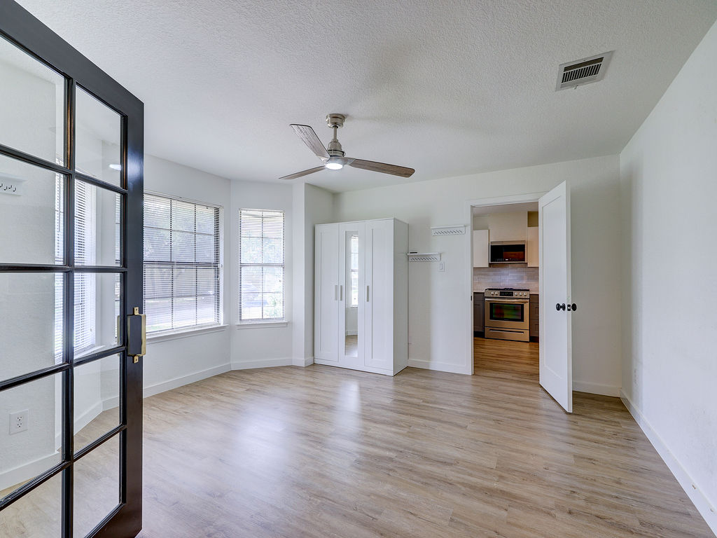 5842 Secrest Drive Austin, TX 78759 - Photo 10 of 40 Well-lit living area with durable flooring, anchored by a sleek ceiling fan and ample window light.