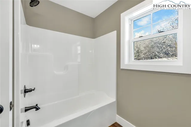 an empty room with wooden floor chandelier fan and windows