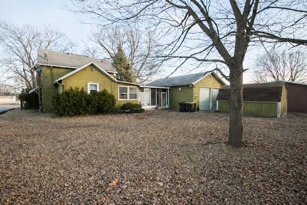 a front view of a house with a yard and large trees