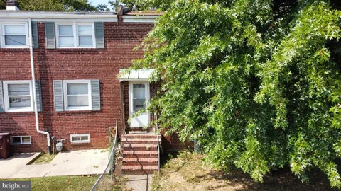a view of a brick house with a yard and large tree
