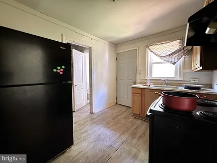 a kitchen with granite countertop a refrigerator and a stove top oven