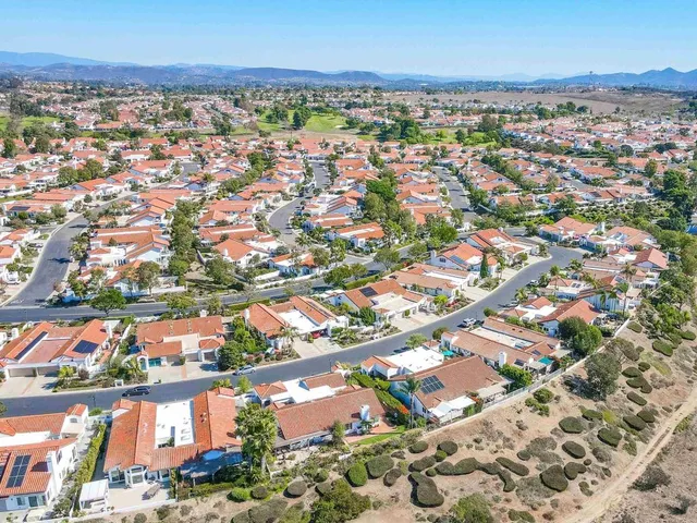 an aerial view of residential houses with outdoor space and trees