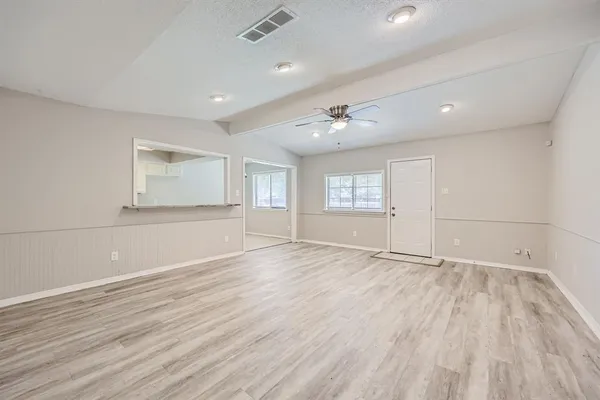 an empty room with wooden floor and windows