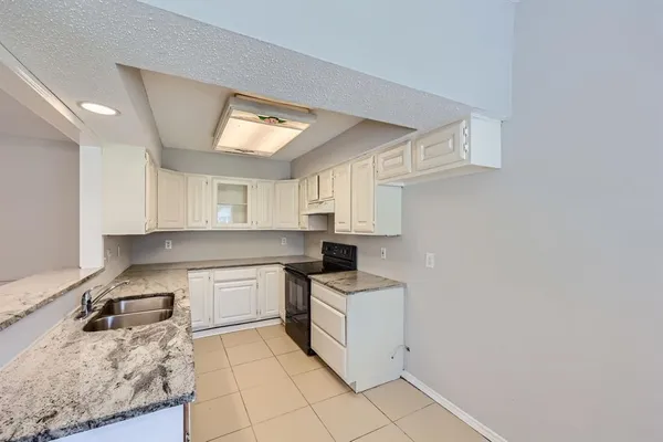 a kitchen with a sink dishwasher stove and white cabinets