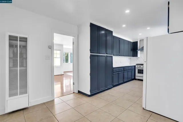 a view of kitchen with refrigerator and white cabinets