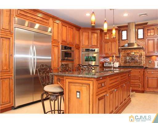 6 Ramsey Road Edison, NJ 08820 - Photo 13 of 25 a kitchen with stainless steel appliances kitchen island granite countertop a refrigerator and wooden cabinets