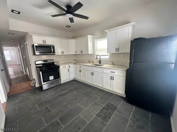 a kitchen with stainless steel appliances granite countertop a sink a stove a refrigerator a microwave oven with white cabinets and a refrigerator