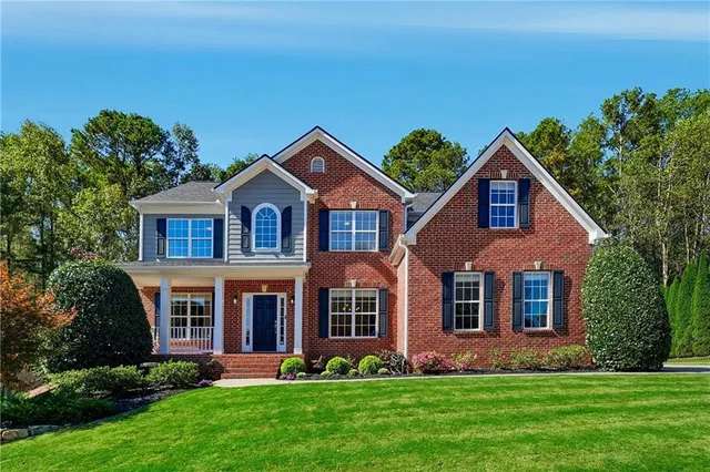 a front view of a house with a yard and trees