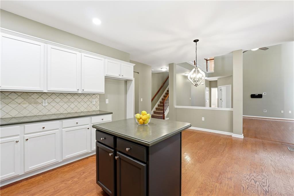 304 Meadowcrest Circle Canton, GA 30115 - Photo 16 of 50 a kitchen with kitchen island granite countertop a stove a sink and white cabinets with wooden floor