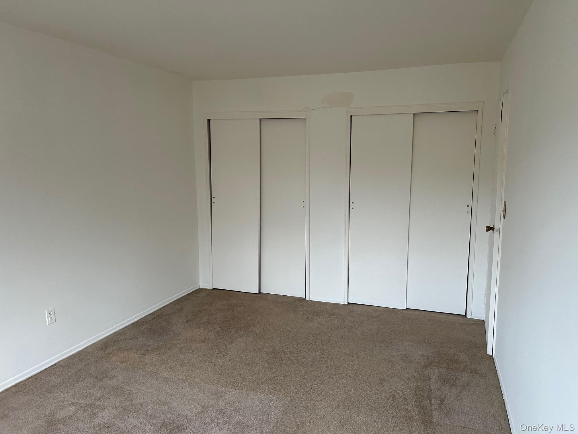122 Sneden Place West, Unit 122 Spring Valley, NY 10977 - Photo 13 of 20 Unfurnished bedroom with two closets and carpet