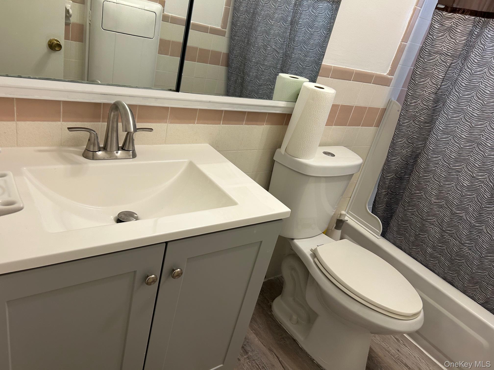 122 Sneden Place West, Unit 122 Spring Valley, NY 10977 - Photo 17 of 20 Bathroom with tile walls, vanity, shower / bath combination with curtain, and dark wood-style floors
