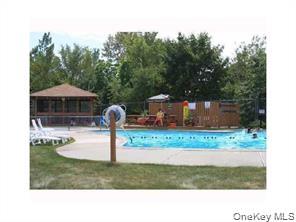 122 Sneden Place West, Unit 122 Spring Valley, NY 10977 - Photo 19 of 20 Community pool featuring a patio area and view of wooded area