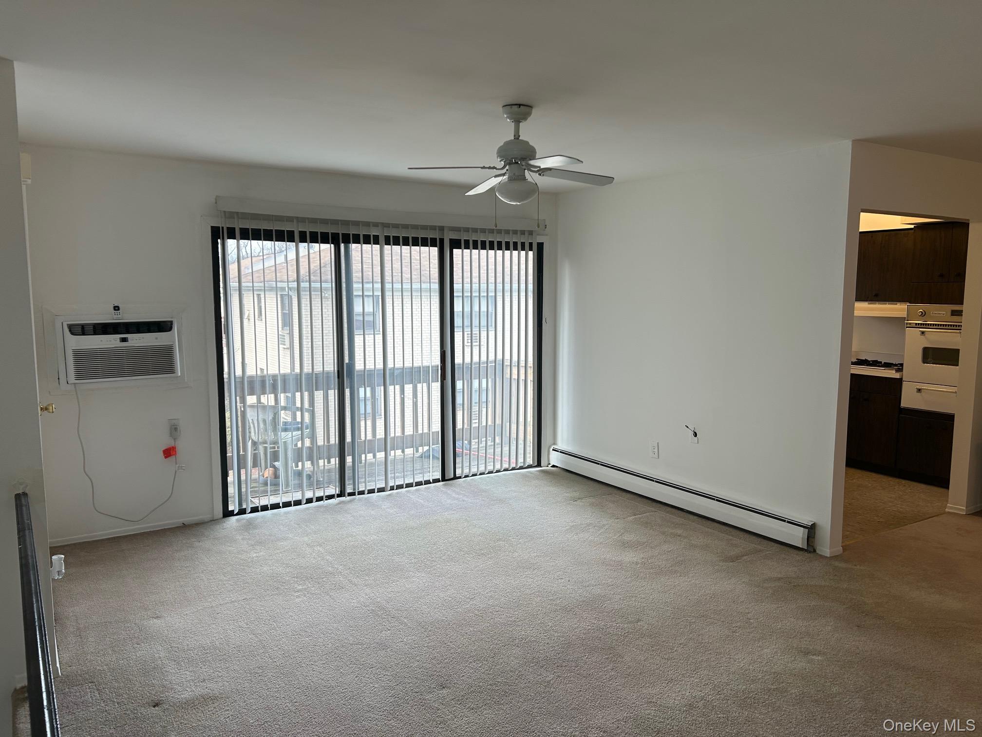 122 Sneden Place West, Unit 122 Spring Valley, NY 10977 - Photo 4 of 20 Unfurnished room featuring baseboard heating, light carpet, a wall mounted air conditioner, and ceiling fan