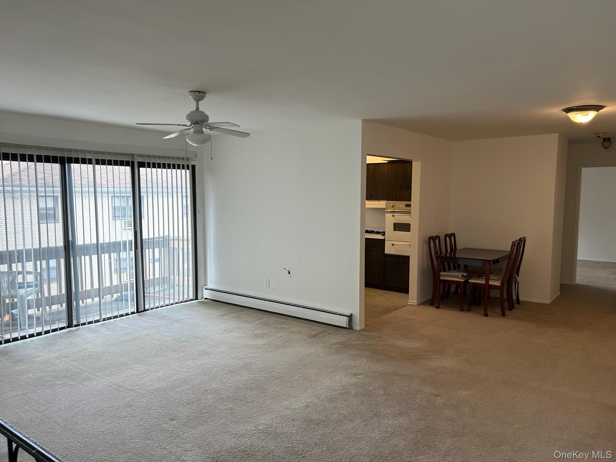 122 Sneden Place West, Unit 122 Spring Valley, NY 10977 - Photo 5 of 20 Unfurnished living room featuring a baseboard radiator, light colored carpet, and a ceiling fan