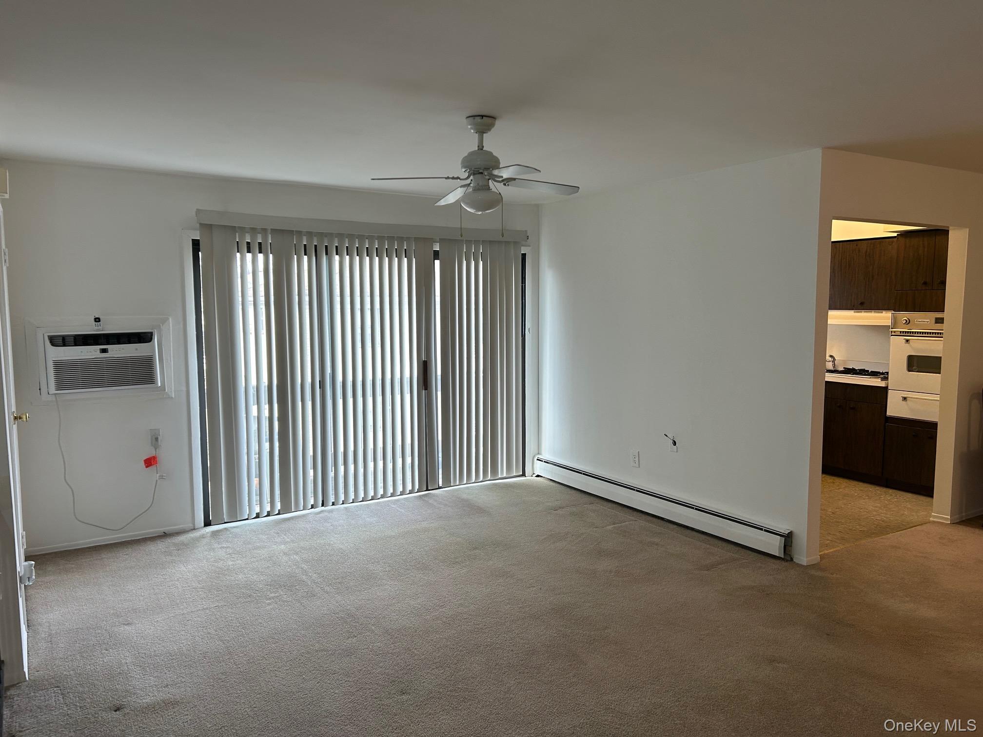 122 Sneden Place West, Unit 122 Spring Valley, NY 10977 - Photo 6 of 20 Spare room with a baseboard heating unit, light colored carpet, ceiling fan, and a wall unit AC