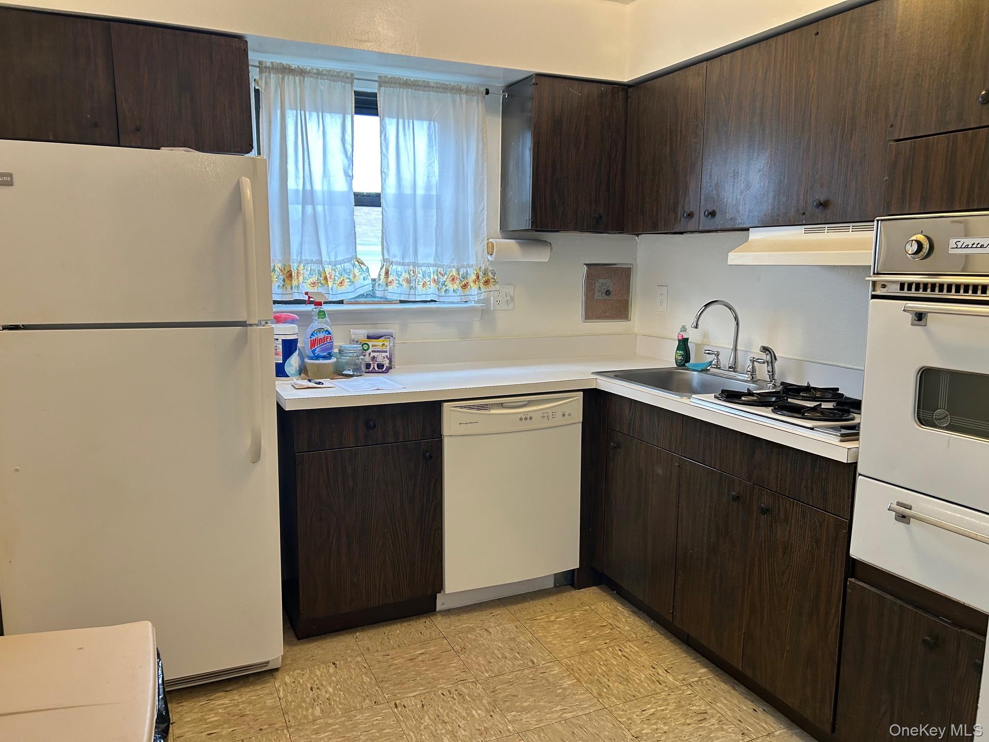 122 Sneden Place West, Unit 122 Spring Valley, NY 10977 - Photo 9 of 20 Kitchen featuring white appliances, dark brown cabinets, light countertops, a warming drawer, and under cabinet range hood