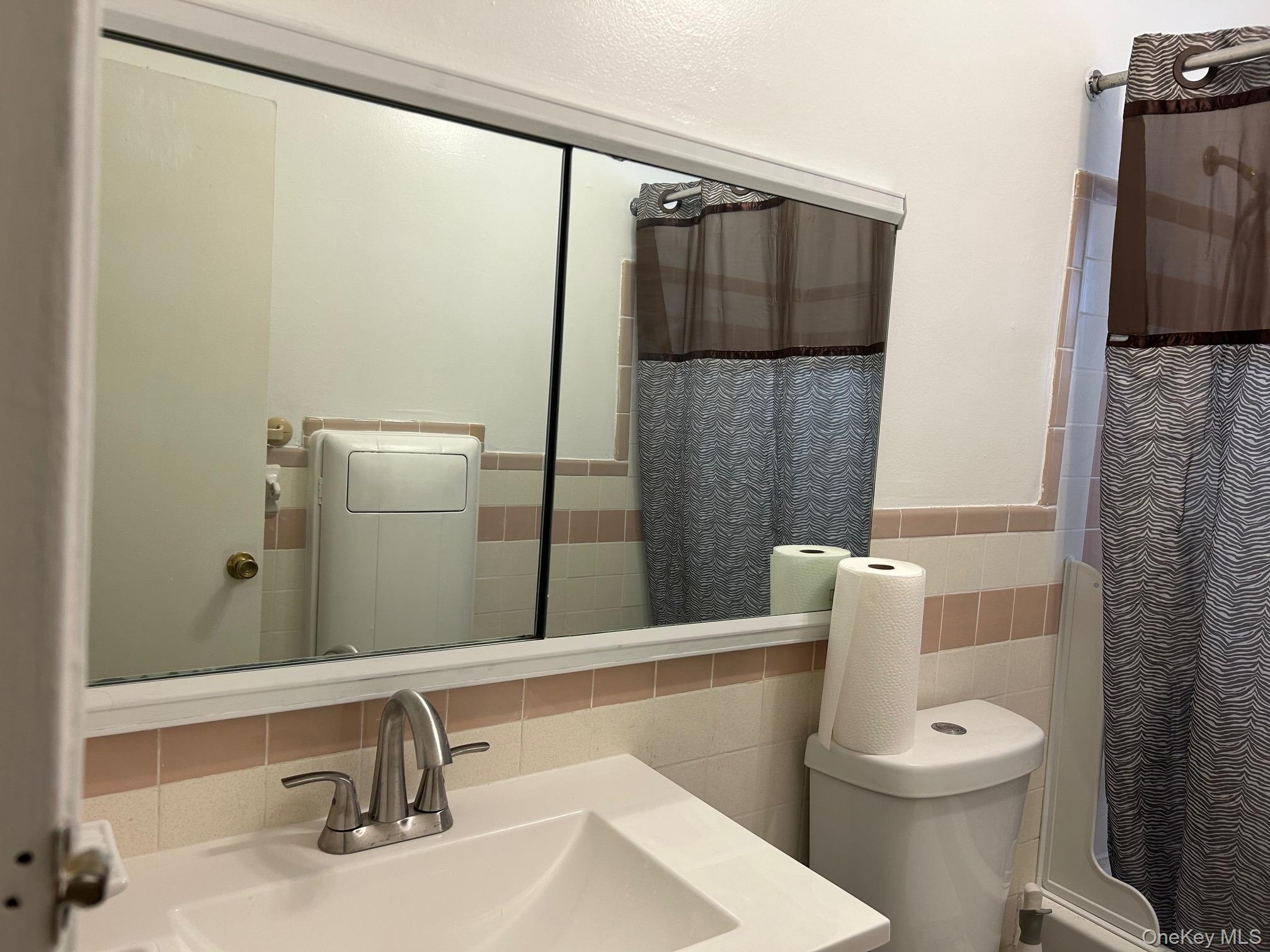 122 Sneden Place West, Unit 122 Spring Valley, NY 10977 - Photo 10 of 20 Full bathroom with tile walls, vanity, a wainscoted wall, and shower / tub combo