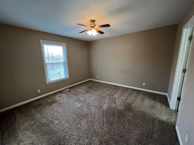an empty room with windows and ceiling fan view