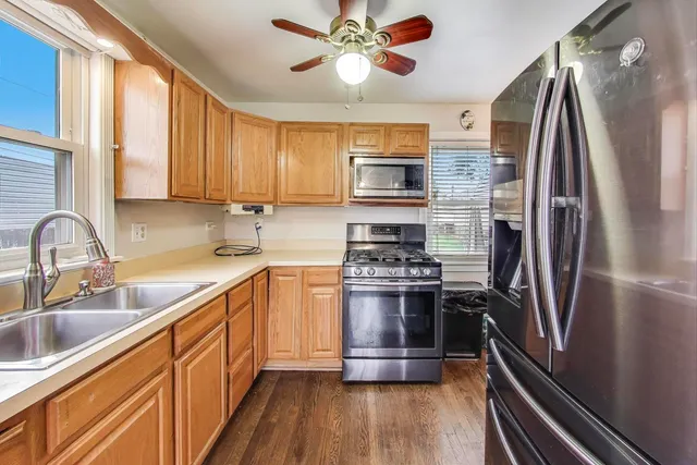 a kitchen with stainless steel appliances a sink a stove a refrigerator cabinets and a window