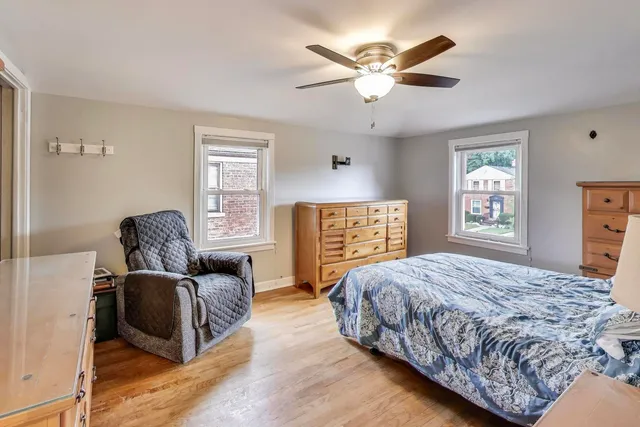 a bedroom with a bed and dresser with wooden floor