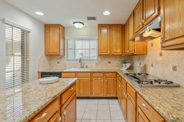 a kitchen with granite countertop a sink stove and cabinets