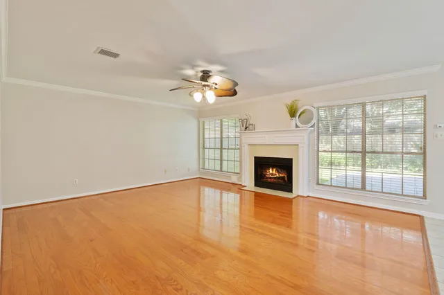a view of an empty room with wooden floor fireplace and a window