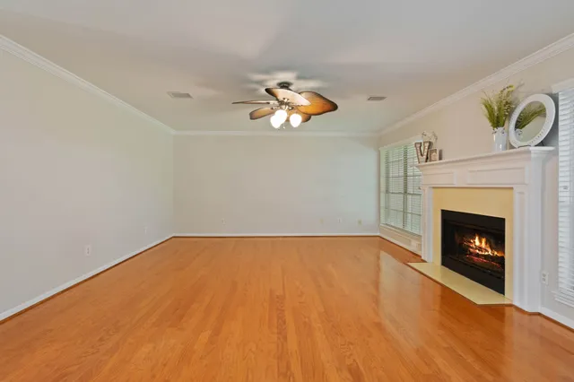 a view of an empty room with wooden floor fireplace and a window