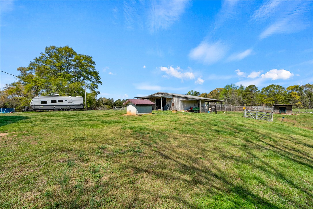801 Princeton Highway Honea Path, SC 29654 - Photo 37 of 49 Expansive green fields offer a serene backdrop for a spacious barn, perfect for various endeavors.