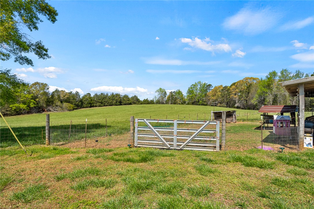 801 Princeton Highway Honea Path, SC 29654 - Photo 38 of 49 This expansive lot features rolling green hills, a sturdy fence, and mature trees under a clear sky.
