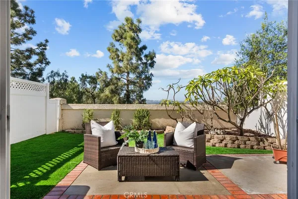 a view of a patio with couches plants and large trees