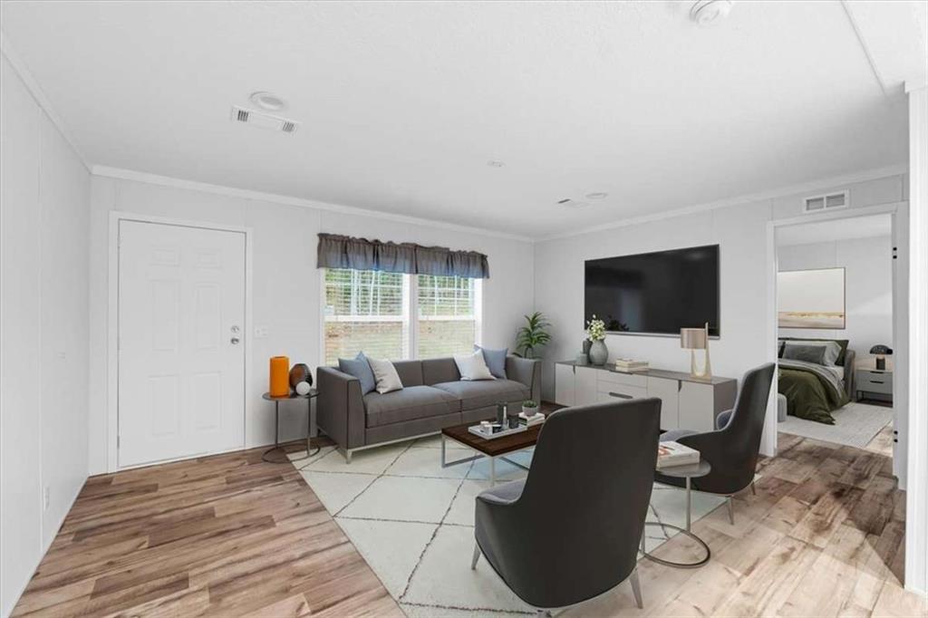 277 Napier Road Southwest Eatonton, GA 31024 - Photo 3 of 34 a living room with furniture a flat screen tv and a floor to ceiling window