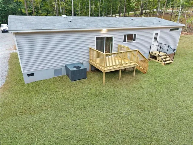 a view of a white house with a big yard and lawn chairs with wooden fence