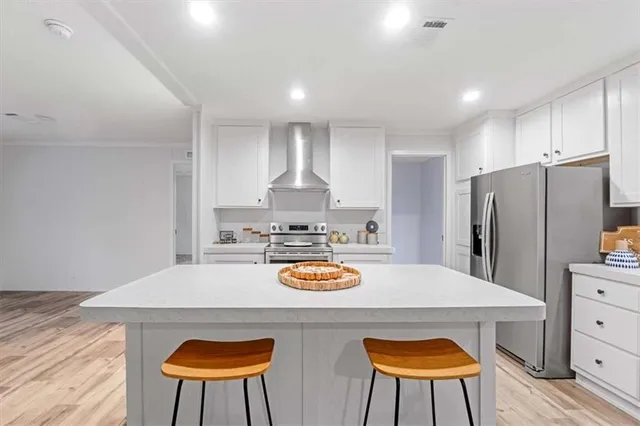 a kitchen with stainless steel appliances granite countertop a refrigerator a stove a sink dishwasher and white cabinets with wooden floor