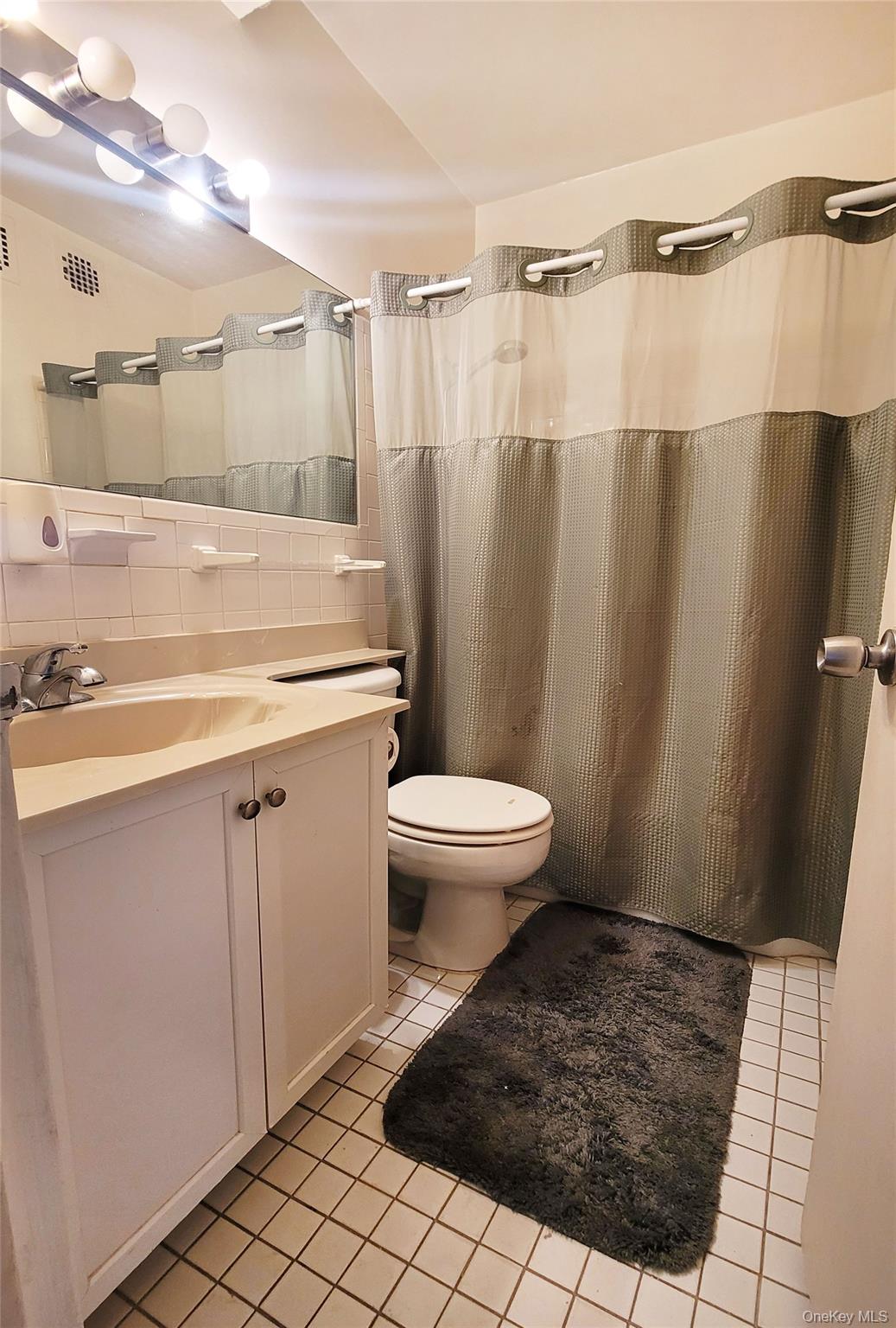 99-72 66th Road, Unit 7AA Queens, NY 11374 - Photo 11 of 19 Full bath with tile patterned flooring, vanity, toilet, tile walls, and a shower with curtain