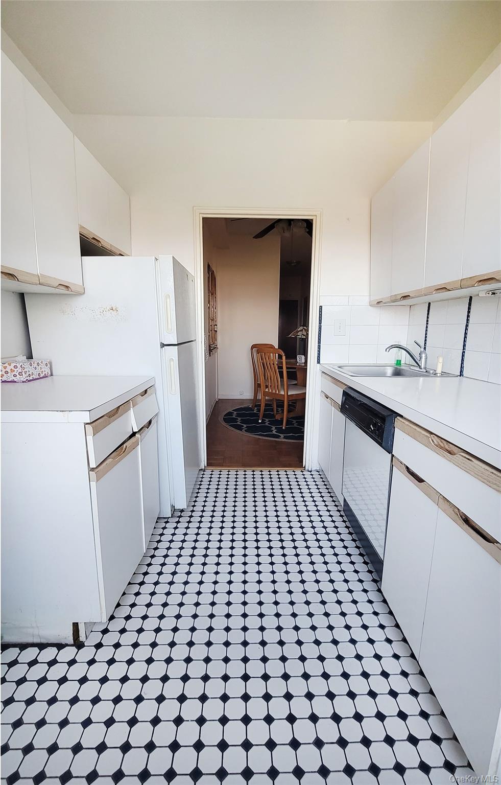 99-72 66th Road, Unit 7AA Queens, NY 11374 - Photo 4 of 19 Kitchen featuring dishwasher, a sink, light countertops, white cabinetry, and decorative backsplash