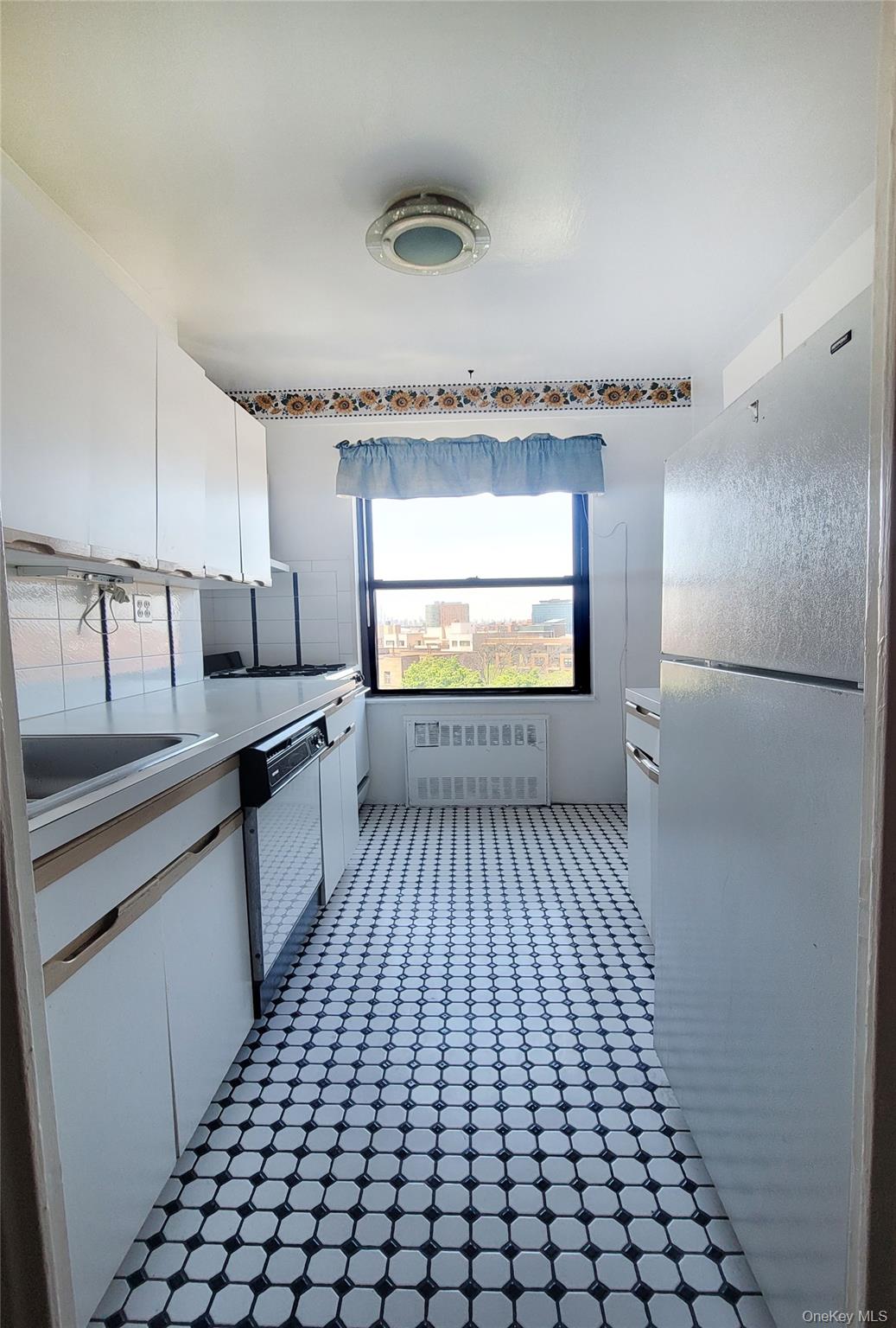 99-72 66th Road, Unit 7AA Queens, NY 11374 - Photo 5 of 19 Kitchen with freestanding refrigerator, radiator, dishwasher, white cabinets, and light countertops